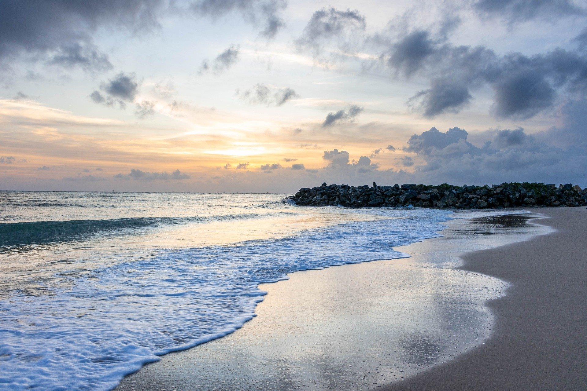 Calm beach with golden sands and serene waves at sunset